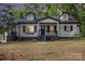 Charming bungalow-style home featuring a covered porch, black shutters, dormers, and mature trees at 1208 Fordham Rd, Charlotte, NC 28208
