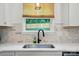 Close-up of the kitchen sink area showcasing quartz countertops and subway tile backsplash at 1212 Mason Way, Mount Holly, NC 28120