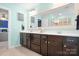 This bathroom features a double sink, a large mirror, dark cabinetry and access to the water closet at 13359 Caite Ridge Rd, Davidson, NC 28036