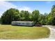 Exterior shot of the home with a well-maintained lawn, gravel driveway, and surrounding trees at 145 Mccreek Dr, China Grove, NC 28023