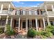 Beautiful brick townhome with a charming front porch, black shutters, and well-manicured landscaping at 155 Harper Lee St, Davidson, NC 28036
