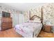 Cozy bedroom features floral wallpaper, hardwood floors, a poster bed, and vintage furniture with closet access at 1574 Jarrett Farm Rd, Newton, NC 28658
