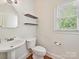 This charming half-bathroom features wood floors, floating shelves, and a classic pedestal sink at 16319 Ashlyn Chase Ct, Charlotte, NC 28277