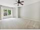 Bright bedroom featuring a large window with white curtains, carpet, and a ceiling fan at 16319 Ashlyn Chase Ct, Charlotte, NC 28277