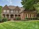 Elegant brick home featuring manicured lawn, covered porch with stately columns, and traditional shuttered windows at 16319 Ashlyn Chase Ct, Charlotte, NC 28277