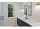 Modern bathroom with a dark vanity, sleek mirror, and window with green view at 1719 Shoreham Dr, Charlotte, NC 28211