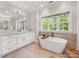 Bright bathroom featuring a soaking tub with wood accent wall and a double sink vanity with light wood flooring at 1900 Nassau Blvd, Charlotte, NC 28205
