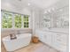 Bright bathroom featuring a soaking tub with wood accent wall, and a double sink vanity with large mirror at 1900 Nassau Blvd, Charlotte, NC 28205