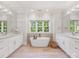 Bright bathroom with double sink vanity, soaking tub with wood accent wall, and light wood look tile flooring at 1900 Nassau Blvd, Charlotte, NC 28205