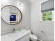 Elegant powder room featuring a marble countertop, round mirror, and natural light from the window at 1900 Nassau Blvd, Charlotte, NC 28205