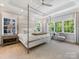 Bright main bedroom with a canopy bed, tray ceiling, and large windows overlooking the lush landscaping at 1900 Nassau Blvd, Charlotte, NC 28205