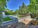 Multi-level backyard featuring an in-ground pool with a safety fence, mature trees and lounge furniture at 2121 Club Rd, Charlotte, NC 28205