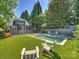 Spacious backyard with artificial turf, a pool area, mature trees, and a covered porch at 2121 Club Rd, Charlotte, NC 28205