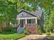 Two-story home featuring a cozy front porch with classic white columns and brick accents surrounded by lush greenery at 2121 Club Rd, Charlotte, NC 28205