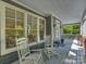 Relaxing front porch with two rocking chairs, gray floors, and views of the lush green surroundings at 2121 Club Rd, Charlotte, NC 28205