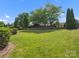 Beautifully landscaped backyard with lush lawn, mature trees, and decorative stone wall at 2467 Chatham Dr, Fort Mill, SC 29707