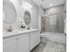Modern bathroom featuring dual sinks, white cabinets, and shower/tub combo with grey tiling at 2467 Chatham Dr, Fort Mill, SC 29707