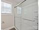 Modern bathroom with a white shower stall and glass door, complemented by a window with blinds at 2502-2504 Glendale Ave, Kannapolis, NC 28081
