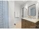 Bathroom with natural wood vanity, travertine floors and patterned shower curtain at 2900 Wickersham Rd, Charlotte, NC 28211