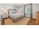 Bright bedroom with hardwood floors, patterned curtains and bedspread, with neutral walls at 2900 Wickersham Rd, Charlotte, NC 28211
