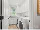 Well-lit laundry room with white cabinets, modern appliances, a window, and plenty of storage space at 2900 Wickersham Rd, Charlotte, NC 28211
