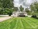 Well-manicured backyard showcasing a charming white brick home with a cozy seating area, perfect for outdoor relaxation at 3128 Country Club Dr, Charlotte, NC 28205