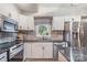 Bright kitchen with stainless steel appliances, neutral stone backsplash and modern white cabinetry at 317 Commodore Loop, Mooresville, NC 28117