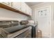 Modern laundry room with sleek black washer and dryer, cabinets and an exterior door at 317 Commodore Loop, Mooresville, NC 28117