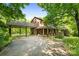 Brick home with a portico and long covered porch, surrounded by lush trees, offering a serene setting at 332 York Spann Rd, Hamptonville, NC 27020