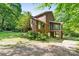 Rear view of brick house with a screened porch and a natural landscape with mature trees at 332 York Spann Rd, Hamptonville, NC 27020