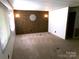 Empty carpeted living room featuring unique wood-accent wall, natural light, and neutral color palette at 44716 Gold Branch Rd, Richfield, NC 28137