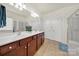 Bright bathroom featuring a double sink vanity with dark wood cabinets and two large mirrors at 54053 Flycatchers Ct, Fort Mill, SC 29707