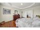 Comfortable main bedroom featuring a tray ceiling, dark wood floors, and ensuite bathroom entrance at 54053 Flycatchers Ct, Fort Mill, SC 29707