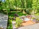 Aerial view of a private backyard with an outdoor kitchen, patio, pergola, mature trees and lush landscaping at 5719 Doncaster Dr, Charlotte, NC 28211