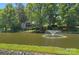 View of a charming home with a pond and fountain, surrounded by lush greenery and mature trees at 5915 Mammoth Rd, Charlotte, NC 28270