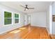 Cozy bedroom featuring hardwood floors, plenty of natural light from large windows, and a modern ceiling fan at 6007 Charing Pl, Charlotte, NC 28211