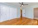 Bright bedroom with hardwood floors, ceiling fan, closets, and an ensuite bathroom at 6007 Charing Pl, Charlotte, NC 28211