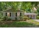 Charming home featuring light brick, black shutters, a screened in porch, and mature landscaping at 6007 Charing Pl, Charlotte, NC 28211