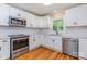 Close-up of a modern kitchen with white cabinets, stainless steel appliances, a subway tile backsplash, and hardwood flooring at 6007 Charing Pl, Charlotte, NC 28211
