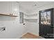 Bright laundry room with white cabinetry, open shelves, and access to the backyard at 6706 Queensberry Dr, Charlotte, NC 28226