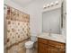 Bright bathroom with a shower-tub, a floral shower curtain, and a wood vanity at 7031 Woodbridge Valley Cir, Charlotte, NC 28227
