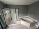 Bathroom showcasing tiled floors, a corner tub, and glass-enclosed shower at 715 Larimer Ln, Charlotte, NC 28262