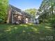 View of the backyard of the home, featuring a cozy deck, green lawn and mature trees at 8017 Nathanael Greene Ln, Charlotte, NC 28227