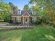 Charming two-story home featuring a well-manicured lawn, landscaped garden, and inviting front porch with decorative flower pots at 8017 Nathanael Greene Ln, Charlotte, NC 28227