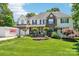 Beautiful home with lush green lawn, mature trees, and a convenient PODS moving container in the driveway at 8056 Stevens Mill Rd, Matthews, NC 28104