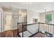 Upstairs hallway featuring wood floors, decorative railing and trim, and multiple entryways with natural light at 8056 Stevens Mill Rd, Matthews, NC 28104