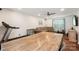 Open-concept living room with a large wooden table, sectional sofa, and a treadmill at 8056 Stevens Mill Rd, Matthews, NC 28104