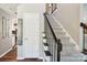 Elegant entryway with a staircase featuring carpeted steps and a dark wood railing, adjacent to a white door at 8056 Stevens Mill Rd, Matthews, NC 28104