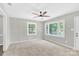 Bright living room featuring plush carpet, a ceiling fan, and large windows offering ample natural light at 8303 Hemby Wood Dr, Indian Trail, NC 28079