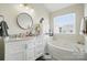 Bright bathroom features a vanity with marble countertop, tub, and a window with natural light at 9204 Washam Potts Rd, Cornelius, NC 28031